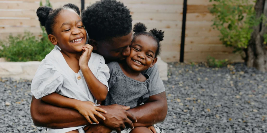 father and daughters hugging